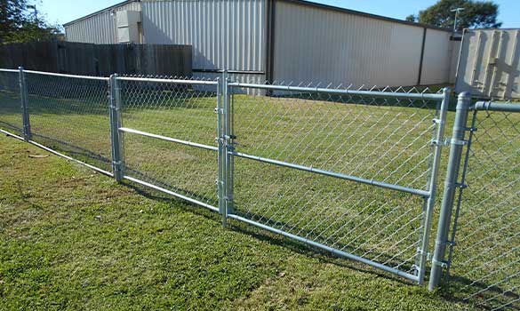 A chain link gate with a warehouse in the background.